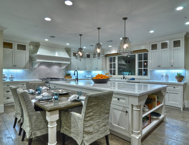 Coastal Kitchen Ideas. Large white kitchen with coastal decor. This white, bright, warm kitchen is beautiful and at the same time functional and family friendly. White custom cabinetry is displayed against distressed planked wood flooring. A dining table attached to the kitchen island make this a place where family and friends are sure to gather. #Kitchen #KitchenIdeas #CoastalKitchen #KitchenDecor