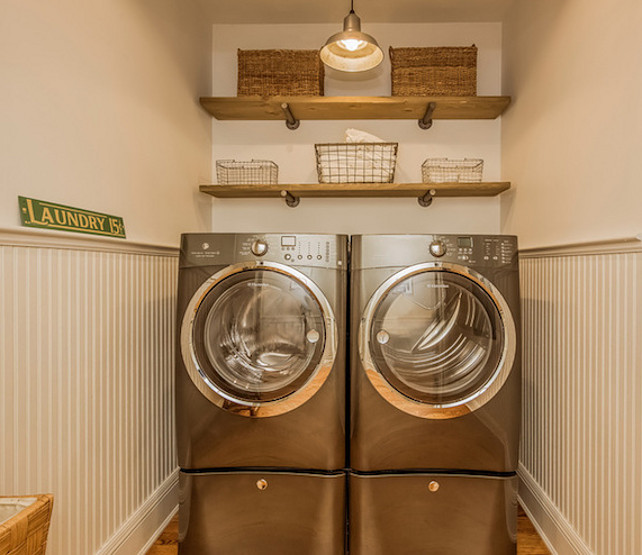 Laundry Room. Gray laundry room boasts light gray on top half of walls and gray beadboard on bottom half of walls framing reclaimed wood shelves filled with woven baskets and wire baskets. #LaundryRoom