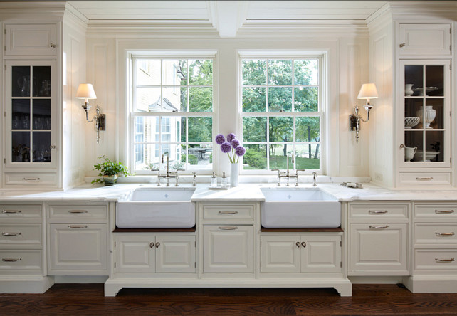 Kitchen Ideas.Dreamy kitchen with sconces flanking two apron kitchen sink. Kitchen sinks alcove with floor to ceiling white cabinets with marble countertops and traditional wood paneling as backsplash. Kitchen hardwood floors. #Kitchen #KitchenIdeas #KitchenDesign #KitchenSink #ApronSink Designed by Yunker Associates Architecture.