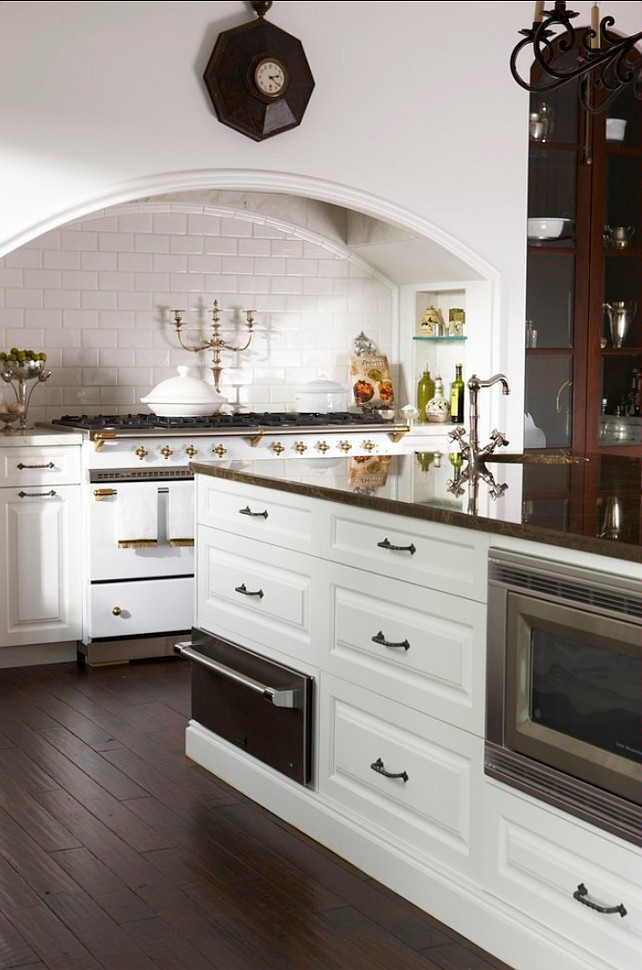 Kitchen Range Ideas. This traditional kitchen boasts intricate details along with thoughtful design. A prep sink adjacent to the white La Cornue range top, a large blower disguised under a cooking niche, and integrated appliance contributes to the effortlessness of the overall space. Traditional Kitchen Range. #Kitchen #Range