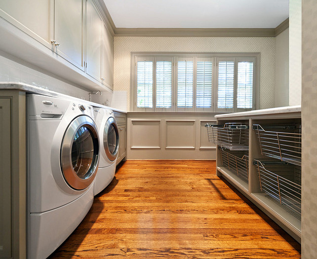Laundry Room Ideas. Huge laundry room with white washer & dryer, gray cabinets, gray painted wainscoting, gray laundry island and wire bins. #laundryRoom #LaundryRoomIdeas