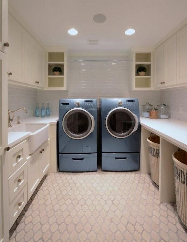.Laundry Room Design. U-shaped laundry room has ivory cabinets with white quartz countertops and subway tiled backsplash atop an arabesque tile floor. Over the blue front-load washer and dryer is a tension rod.