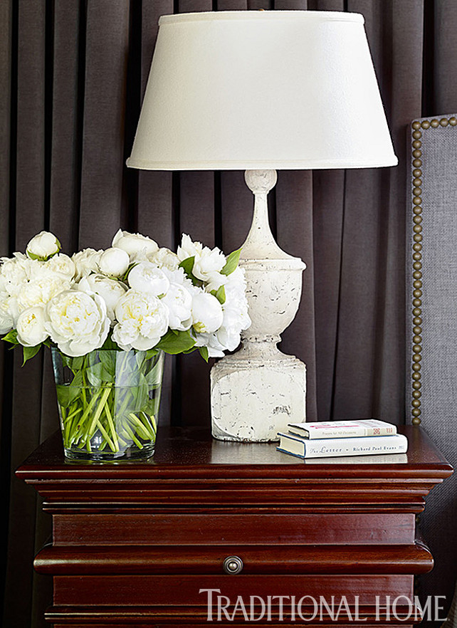 Nightstand Decor. Nightstand Decor Ideas. The nightstand, in Hand Rubbed Brown, blends with the dark hues of the master bedroom. White accents, like the lamp from Bungalow Classic and a vase of roses provide contrast. #Nightstand #NightstandDecor #Bedroom