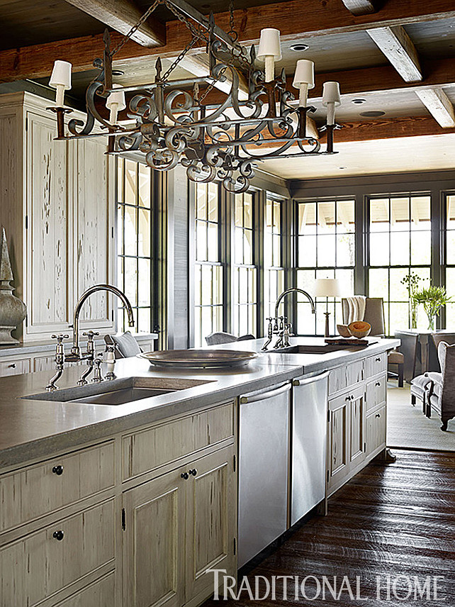 Rustic Kitchen Ideas. Beautiful Kitchen with rustic elements. Inspiring kitchen island with two large Kohler sinks fitted with Waterworks bridge-style faucets. Countertop is concrete. The iron chandelier is from Foxglove Antiques. #Kitchen #RusticKitchen #KitchenIsland