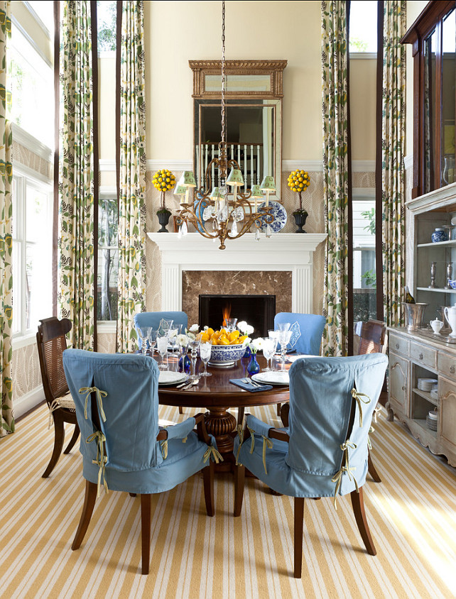 Dining Room. A dedicated dining room – with 20-foot-high ceilings – is situated on the site of the former traditional living room and features understated touches such as blue slip covered chairs and a yellow and white striped carpet. 