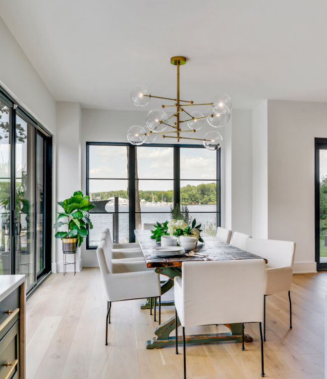 The open floor plan is designed to capture the essence of seaside living featuring large windows that flood the space with natural light and offer breathtaking views of the water #diningroom #naturallight