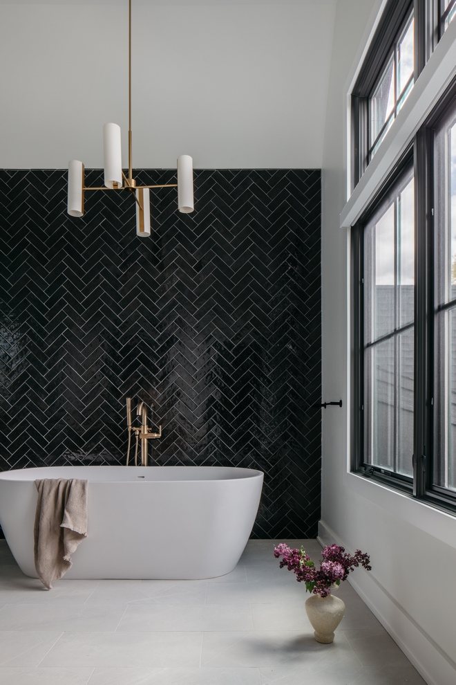 This entire wall which runs behind the freestanding tub all the way to the shower, is accentuated with a bestseller textured black tile in a herringbone pattern #herringbonetile