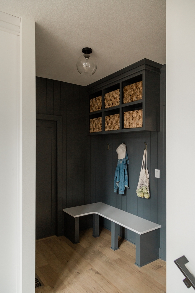 The mudroom features custom bench with white quartz top and upper cabinets Vertical shiplap on walls create an uniform look to this entire space Simple economical and beautiful