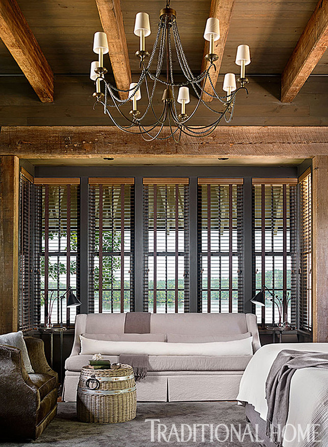 Bedroom Sitting Area. Master Bedroom Sitting Area Ideas. Rough-hewn posts trim a window sitting spot in the master bedroom. A sofa and chair in gray tones coordinate with the bed. Chandelier is the “Marigot Eight Light Chandelier” from Circa Lighting. Sofa is the “Landau Devan Skirted Sofa” by Lee Industries. Sofa fabric: “Elements 09” #3655209 from Fabricut. Long lumbar pillow on sofa: “Patterson”/Ivory #0212703 also from Fabricut. #BedroomSittingArea #SittingArea #MasterBedroomSittingArea