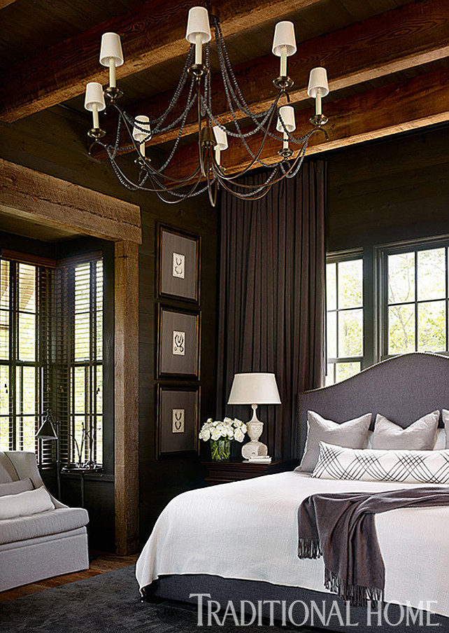 Bedroom. Master Bedroom Ideas. Classy and rustic master bedroom design. Floor-to-ceiling draperies close behind the camel-backed gray upholstered headboard. Chandelier is the Marigot Eight Light Chandelier from Circa Lighting. The master bedroom mixes rustic finishes with tailored decor. I love this look! The bed, a 54-inch-high camel-back upholstered king bed, was custom designed by Douglass Workroom. Long lumbar pillow on bed is the “Valence”/Dove #11158-01 from Cowtan & Tout. Bedding is by Donna Karan Collection. #Bedroom #MasterBedroom #MasterBedroomDesign #MasterBedroomIdeas #MasterBedroomDecor