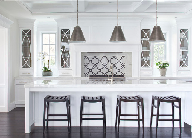 Kitchen. White Kitchen with custom designed backsplash, dark hardwood floors and large island. The pendants are by "Visual Comfort, Goodman Small Hanging Lights". Kitchen Hardware: The hardware is "Top Knobs Square Bar Pull M1286". The counter stools were custom-made for the clients. The backsplash is a customized natural stone mosaic available through "Famosa Tile". Countertop is "Calacatta Marble". #Kitchen #WhiteKitchen